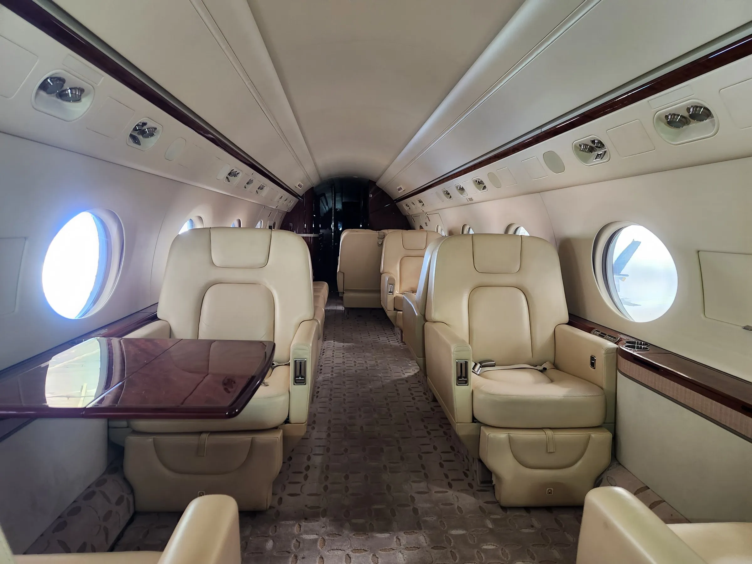 Private jet cabin with cream leather seats and a wood table after interior detailing.