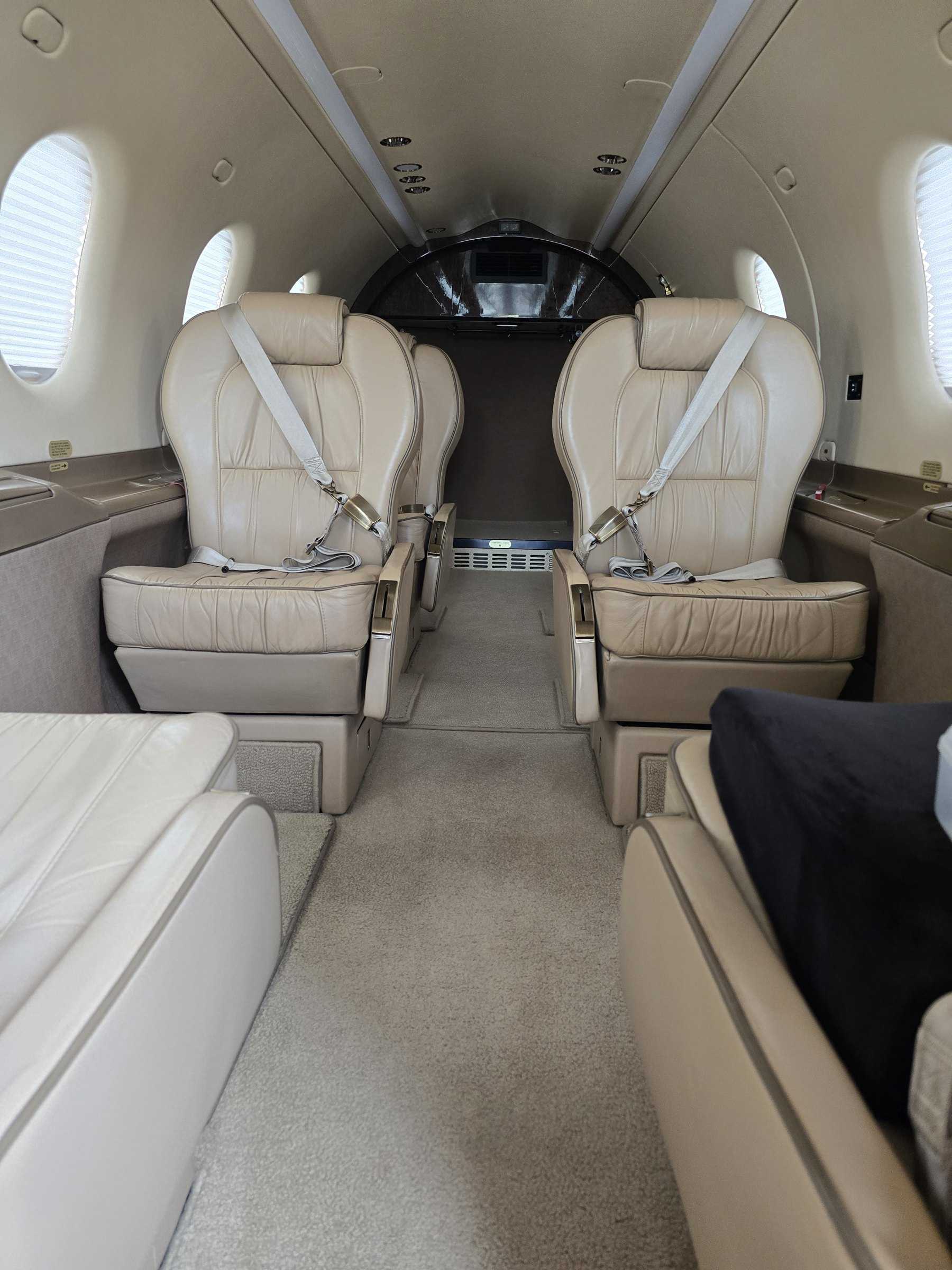 Cream leather aircraft cabin seats with seatbelts after cleaning and conditioning.