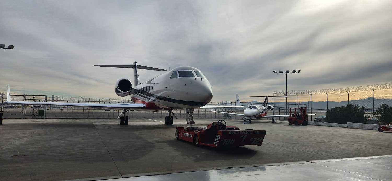 Two private jets parked on a Las Vegas tarmac at sunrise after exterior detailing.