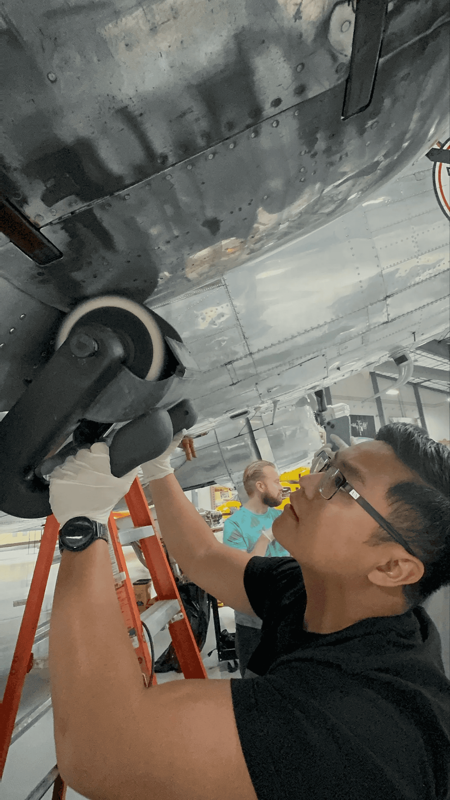 Polished aircraft brightwork showing rivets and mirror-like reflection on a red and black aircraft.