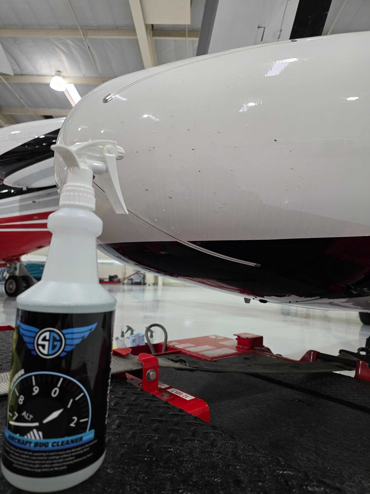 Aviation bug remover spray bottle next to the leading edge of a private aircraft before detailing.