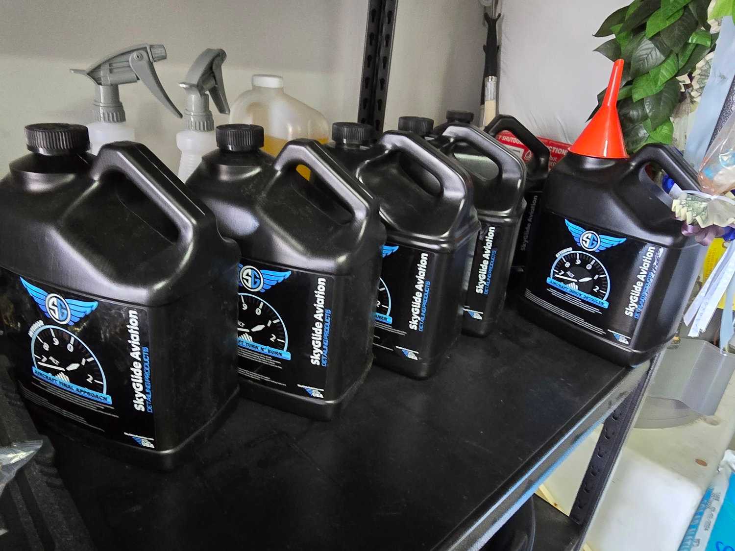 Skyglide aviation-grade detailing product jugs lined up in the Crystal Skies workshop.